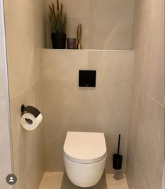 a white toilet sitting in a bathroom next to a wall mounted toilet paper dispenser