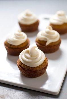 several cupcakes with white frosting on a plate