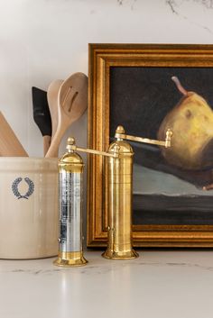 a painting and some kitchen utensils on a counter next to a gold canister