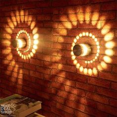 three circular lights are shining on a brick wall in front of a stack of books