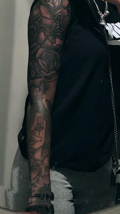 a man with tattoos on his arm holding a cell phone