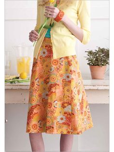 a woman standing in front of a counter holding a flower and wearing a yellow jacket