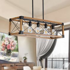 a chandelier hanging over a dining room table with flowers in the vases