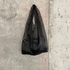 a black bag hanging on the side of a concrete wall with no one around it