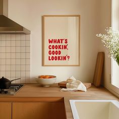 a kitchen with a bowl of fruit on the counter and a framed poster above it