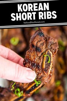 a hand holding up a piece of korean short ribs in front of the camera and text overlay that reads, korean short ribs