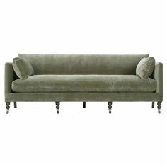 a green velvet couch with two pillows on the back and one arm upholstered