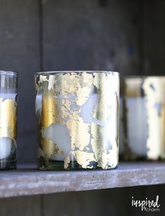 three candles sitting on top of a shelf next to each other