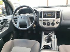 the interior of a small car with dashboard controls and steering wheel, dash lights on