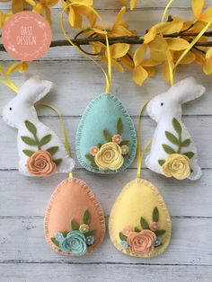 three easter eggs decorated with flowers and leaves on a white wooden surface next to yellow flowers