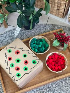 a wooden tray topped with two boxes filled with candy next to a potted plant