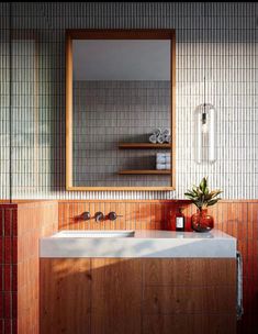 a bathroom sink sitting under a mirror next to a wooden cabinet and counter top in front of a tiled wall