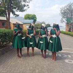 four women in green dresses are standing on the street