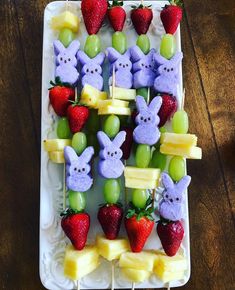 an assortment of fruits and snacks on a plate with strawberries in the shape of bunnies