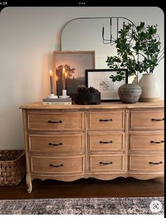 a wooden dresser topped with lots of drawers next to a mirror and potted plant