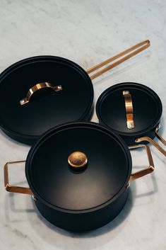 three black pots with gold handles on a white counter