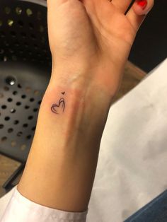 a woman's wrist with a small heart tattoo on the left side of her arm