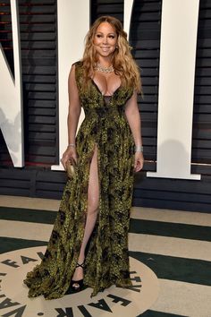 a woman in a long green dress posing for the camera at an oscars event