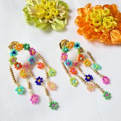 Delicate chandelier earrings made of seed-beaded daisy-covered rings with dangling daisy beaded drops. Earrings measure about 3/4” wide x 2-1/8” long and are lightweight. Plated brass posts. Spring Dangle Beaded Earrings, Bohemian Spring Jewelry With Dangling Beads, Bohemian Jewelry With Dangling Beads For Spring, Spring Dangle Jewelry With Dangling Beads, Bohemian Beaded Earrings With Flower Charm, Small Loop Earrings, Bead Charms Diy, Loop Earrings, Seed Bead Earrings