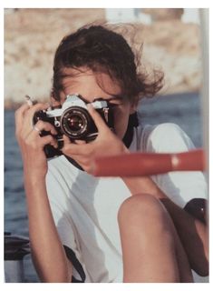 a person sitting on the ground with a camera in front of their face, taking pictures