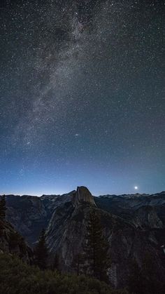 the night sky with stars above mountains and trees