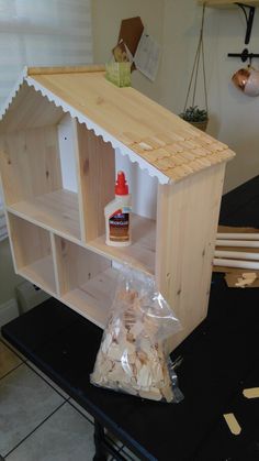 an unfinished dollhouse shelf with glue and wood shavings on the shelves next to it