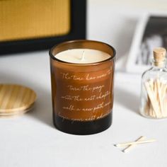 a candle sitting on top of a table next to some matches and a glass bottle