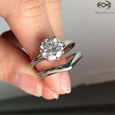 a woman's hand holding a ring with a diamond in it and the top part of her finger