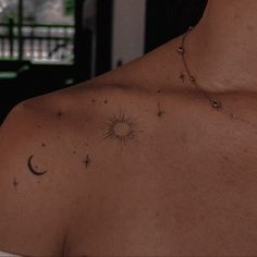 the back of a woman's shoulder with stars and moon tattoos on it,