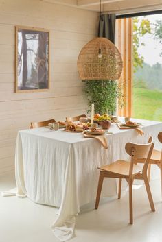 a dining room table is set with plates and bowls on it, along with two wooden chairs