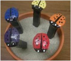 four little ladybugs are sitting in a flower pot on the table, each painted different colors