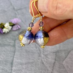 ✦Add a touch of elegance to your jewelry collection with these stunning Purple and Gold Murano Glass Bead Earrings. These unique earrings make the perfect gift for mom or a special someone in your life.  ✦The handcrafted brilliant Italian Murano glass Venetian beads round beads have beautiful colorful hues of dark purple with gold and silver interior foil to create a stunning look. The beads measure 12mm and are accented with purple Swarovski 4mm bicone crystals.  ✦Earring length is approximately 1.5 inches.  ✦The high quality, 14k gold filled leverback ear wires ensure a secure fit. Also available with simple 14k gold filled French hook ear wires. Please select ear wire style at check out. ✦Want to upgrade your earrings with solid 14k gold ear wires? Click here to purchase the upgrade: ht Glass Bead Earrings, Diy Jewelry Projects, Earrings Round, Murano Glass Beads, Leverback Earrings, Jewelry Card, Perfect Gift For Mom, Bead Earrings, Jewelry Projects