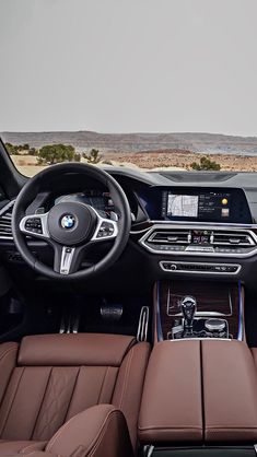 the interior of a bmw car with brown leather seats and steering wheel, dashboard, and center console