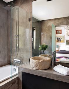 a bathroom with a sink, mirror and bathtub next to a bed in the background