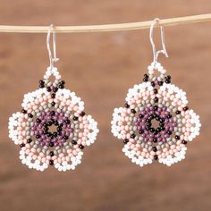 two pairs of beaded earrings hanging from a clothes line on top of a wooden table