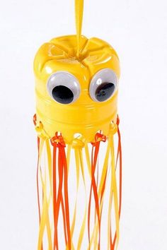 a yellow object with googly eyes on it's head and long red strings