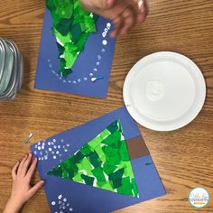 two children are making paper trees on the table