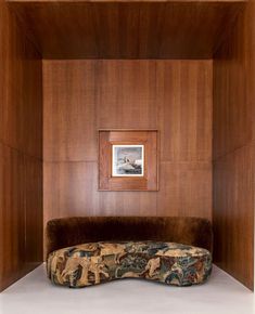 a couch sitting in the corner of a room with wood paneling on the walls