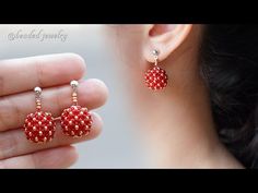 the woman is wearing red beaded earrings with gold beads on it's ear