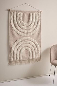 a chair sitting next to a wall hanging with a rug on it's side