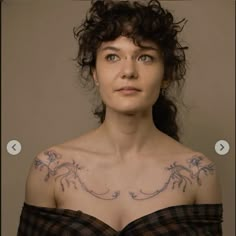 a woman with tattoos on her chest looking at the camera