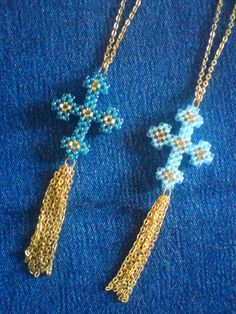 two cross pendants are shown on a blue cloth with gold chains and beading