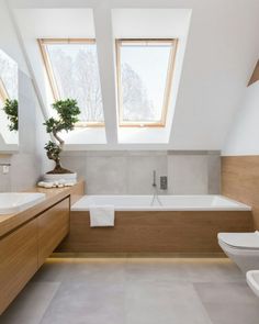 a modern bathroom with skylights above the bathtub and sink area is featured in this magazine