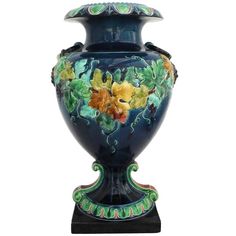 a large blue vase with flowers painted on the outside and green trim around the top