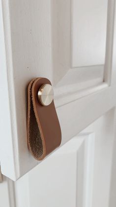 a close up of a door handle on a white door with brown leather handles and an oval knob