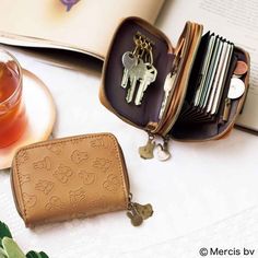 an open wallet sitting on top of a table next to a tea cup and book