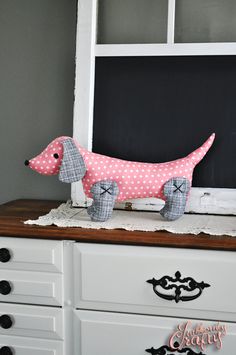 a pink dachshund dog sitting on top of a dresser