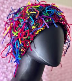 a black mannequin head with multicolored yarn on it's side