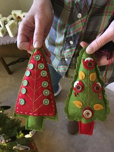 two christmas trees made out of felt with buttons on them are being held by someone's hands