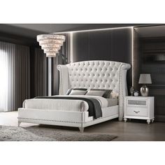 a white bed sitting in a bedroom next to a night stand and nightstand with a chandelier hanging from the ceiling